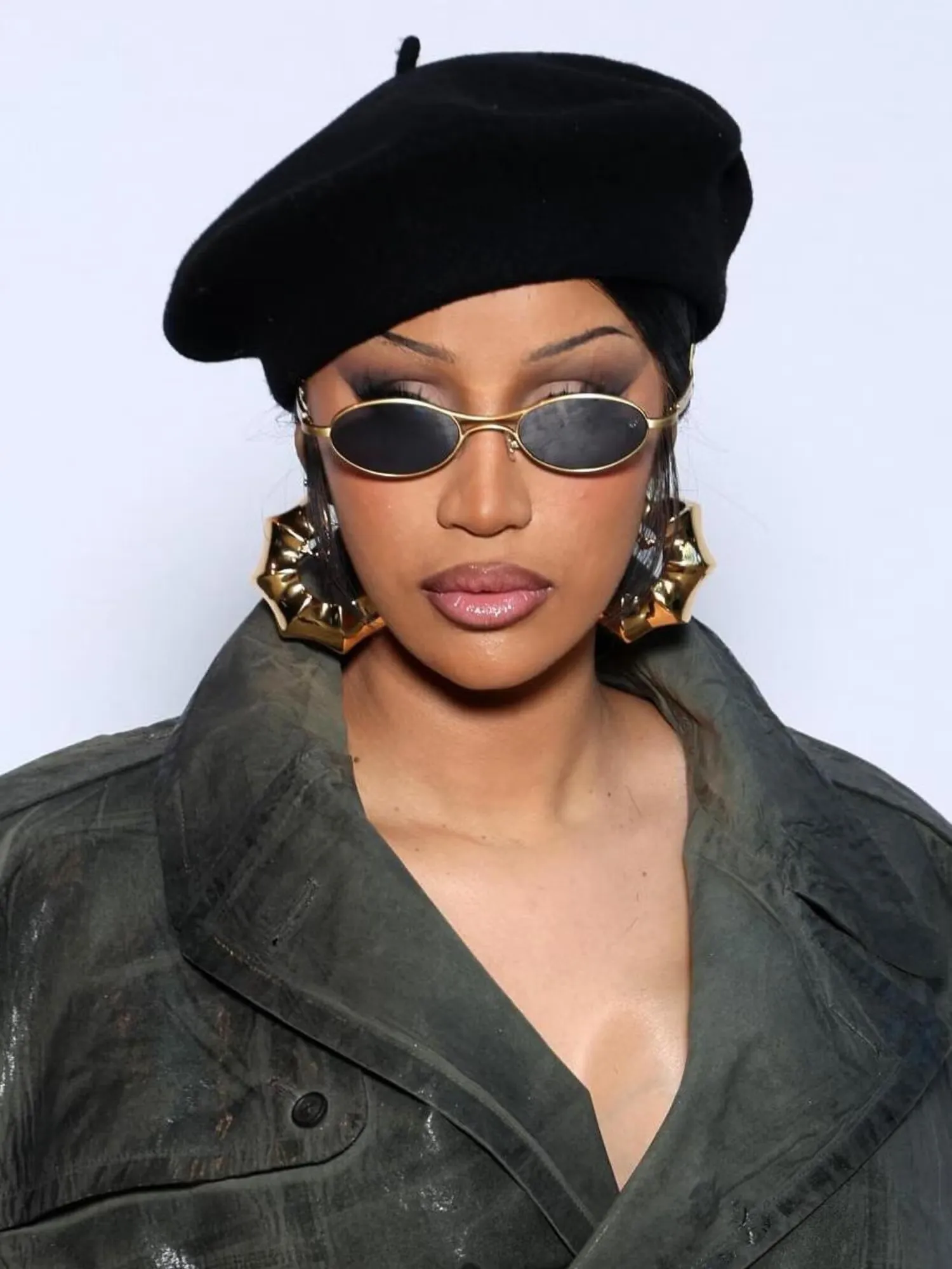 Cardi B en béret noir, petites lunettes de soleil ovales à monture dorée et grandes créoles dorées