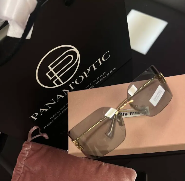 Lunettes de soleil Miu Miu sur leur boîte, à côté d'un sac Panam'Optic