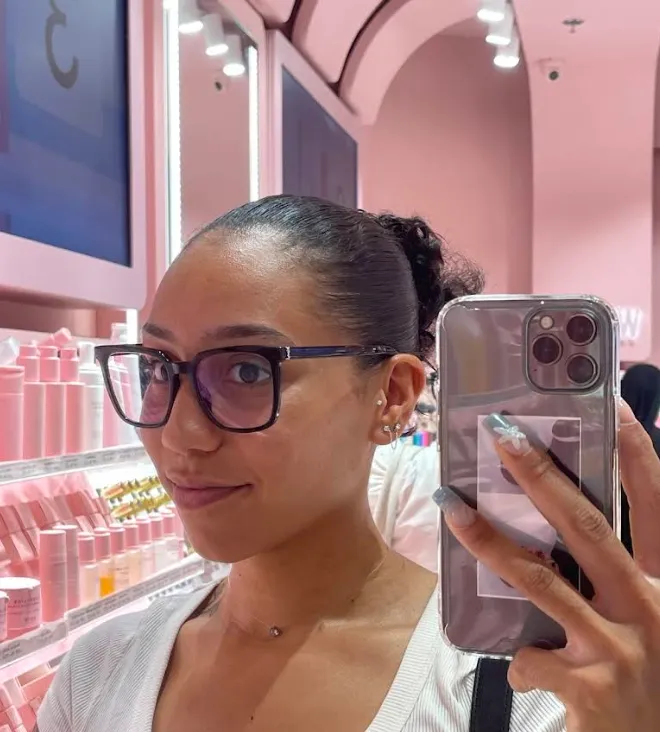 Cliente portant une monture noire carrée, en photo dans un miroir